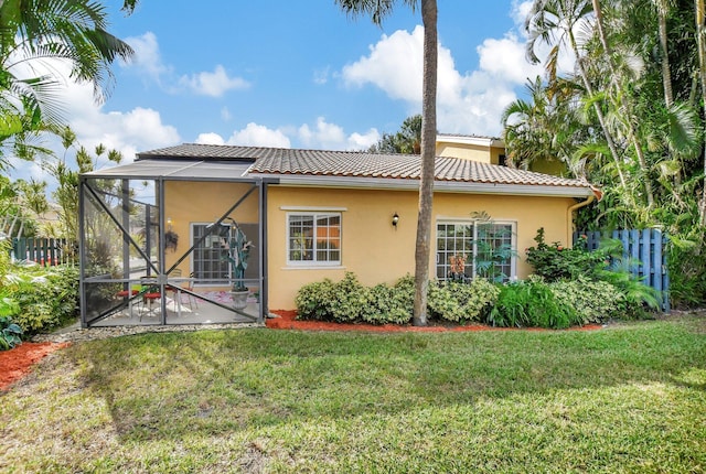 back of property with a yard, a patio area, and a lanai