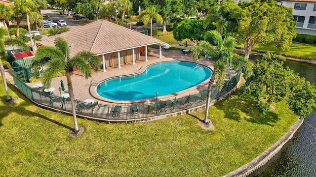 view of swimming pool with a patio area, a yard, and a water view