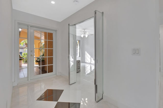 doorway featuring ceiling fan and light tile patterned flooring