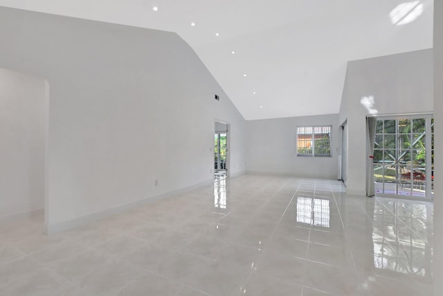 empty room with light tile patterned floors and high vaulted ceiling