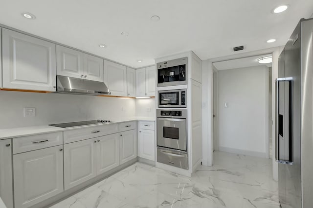 kitchen with marble finish floor, a warming drawer, light countertops, appliances with stainless steel finishes, and under cabinet range hood