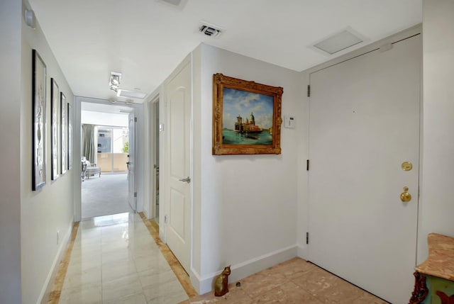 hallway featuring visible vents, attic access, and baseboards