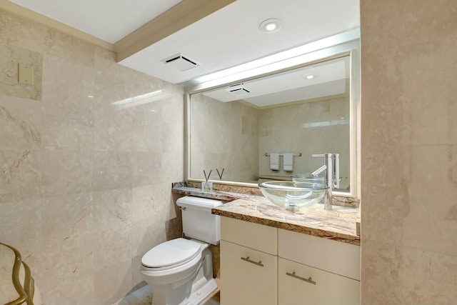 bathroom featuring visible vents, tile walls, toilet, and vanity