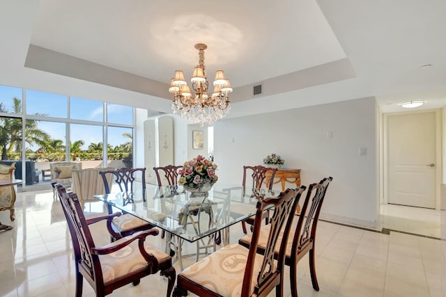 dining area with a tray ceiling, arched walkways, visible vents, a chandelier, and baseboards