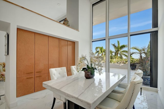 dining space featuring marble finish floor and a high ceiling