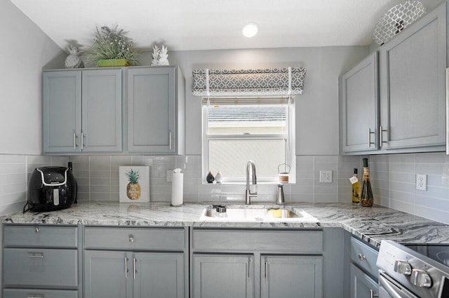 kitchen with tasteful backsplash, stainless steel electric range oven, gray cabinetry, and sink