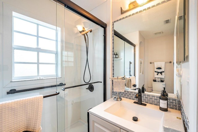 bathroom with decorative backsplash, vanity, and a shower with door