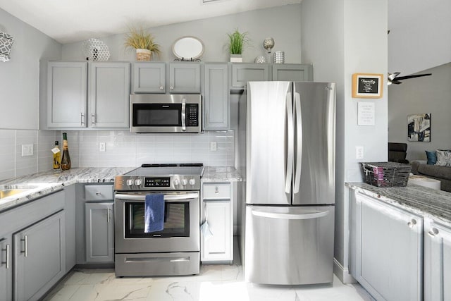 kitchen with appliances with stainless steel finishes, tasteful backsplash, lofted ceiling, and gray cabinetry