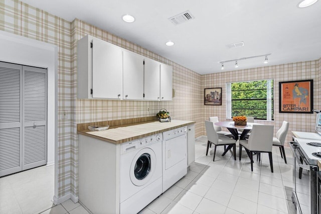 clothes washing area featuring light tile patterned floors and washing machine and dryer