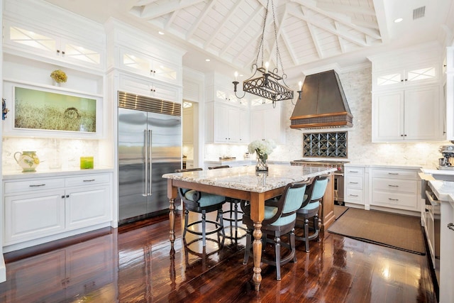 kitchen with white cabinetry, hanging light fixtures, custom exhaust hood, and premium appliances