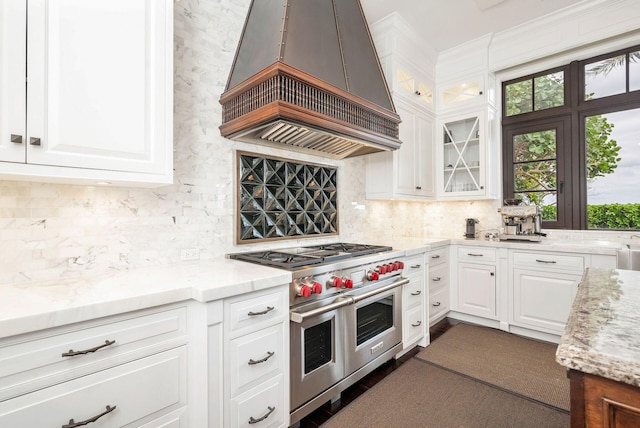 kitchen featuring light stone countertops, white cabinetry, double oven range, and custom exhaust hood