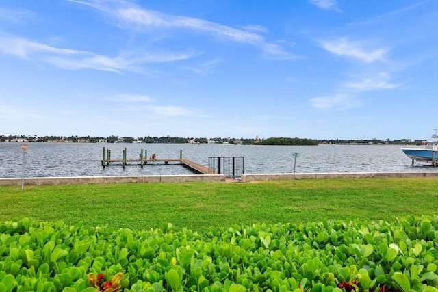 view of dock with a lawn and a water view