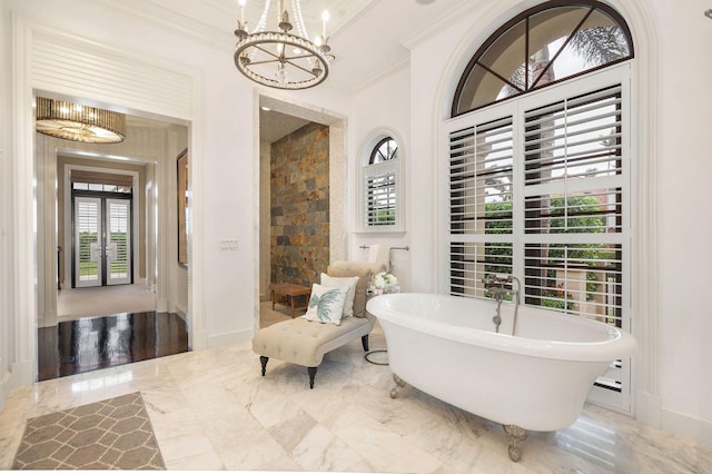 bathroom with a notable chandelier, crown molding, a tub to relax in, and french doors