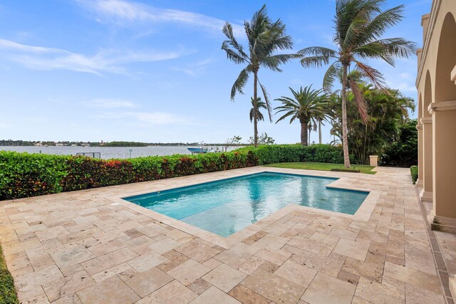 view of swimming pool featuring a patio and a water view