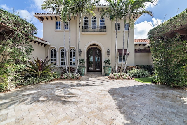 mediterranean / spanish house featuring a balcony and french doors