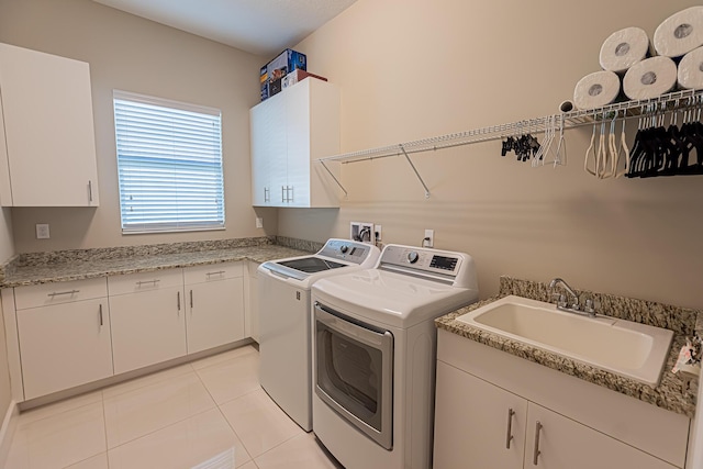 washroom featuring separate washer and dryer, sink, light tile patterned floors, and cabinets