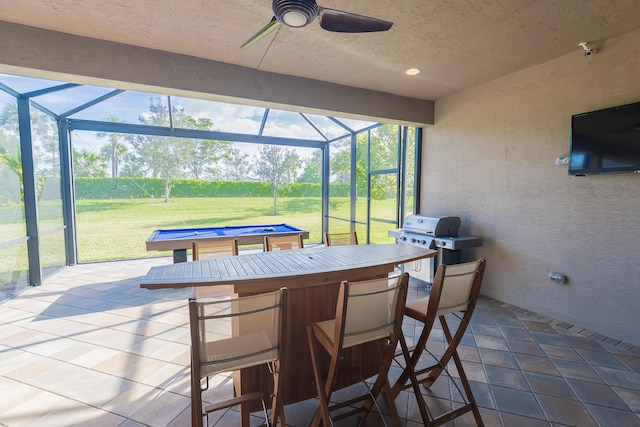 view of patio featuring glass enclosure, an outdoor bar, grilling area, and ceiling fan