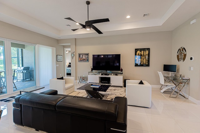 tiled living room featuring a raised ceiling and ceiling fan