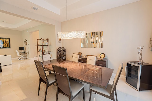 dining space with a tray ceiling, wine cooler, and an inviting chandelier