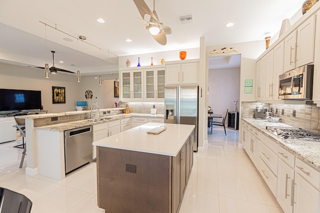 kitchen with a kitchen breakfast bar, stainless steel appliances, ceiling fan, and a large island