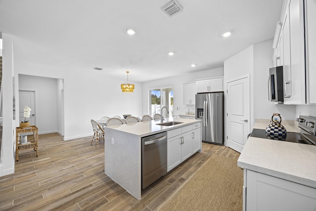 kitchen with white cabinetry, a center island with sink, light hardwood / wood-style floors, and appliances with stainless steel finishes