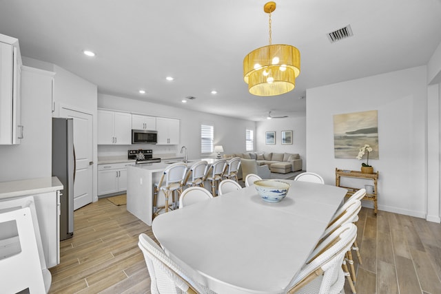 dining room featuring ceiling fan with notable chandelier and light wood-type flooring