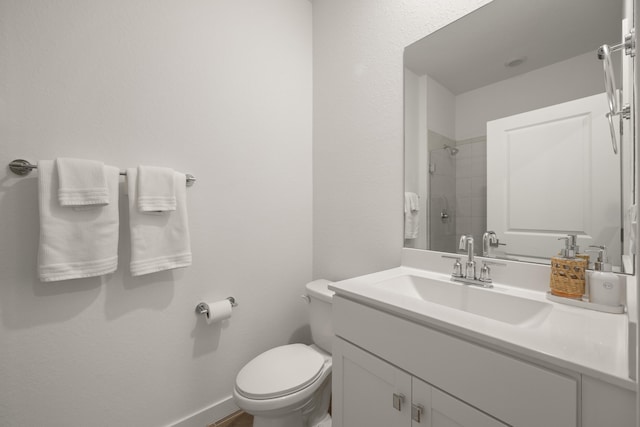 bathroom featuring tiled shower, vanity, and toilet