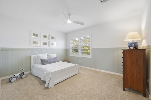 bedroom with carpet flooring, ceiling fan, and wood walls