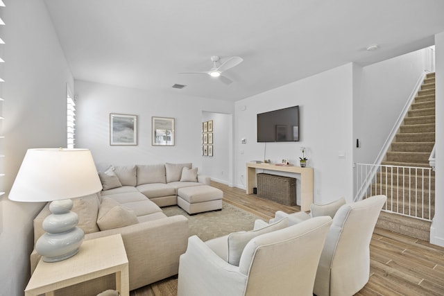 living room with ceiling fan, a fireplace, and light hardwood / wood-style flooring