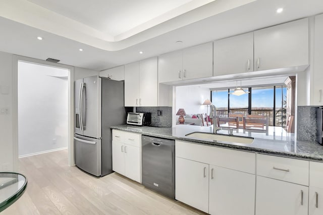 kitchen featuring stainless steel fridge with ice dispenser, white cabinetry, dark stone countertops, dishwasher, and sink