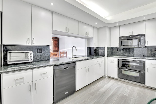 kitchen featuring backsplash, black appliances, sink, light hardwood / wood-style flooring, and white cabinetry