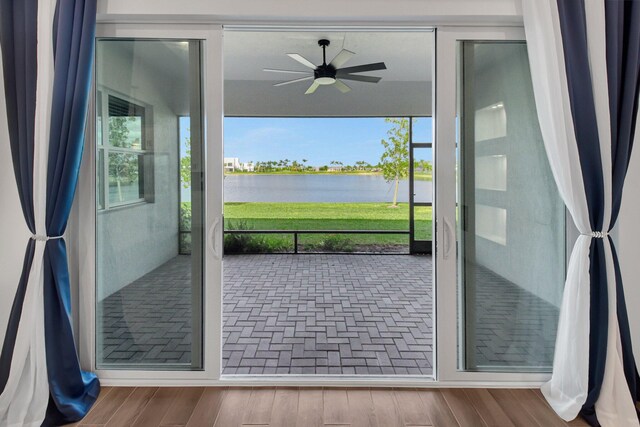 unfurnished living room with a raised ceiling, a water view, light hardwood / wood-style flooring, and ceiling fan