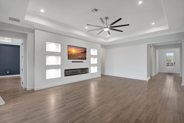 unfurnished living room with hardwood / wood-style flooring, ceiling fan, and a tray ceiling