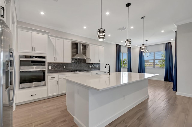 kitchen featuring pendant lighting, white cabinets, and wall chimney exhaust hood