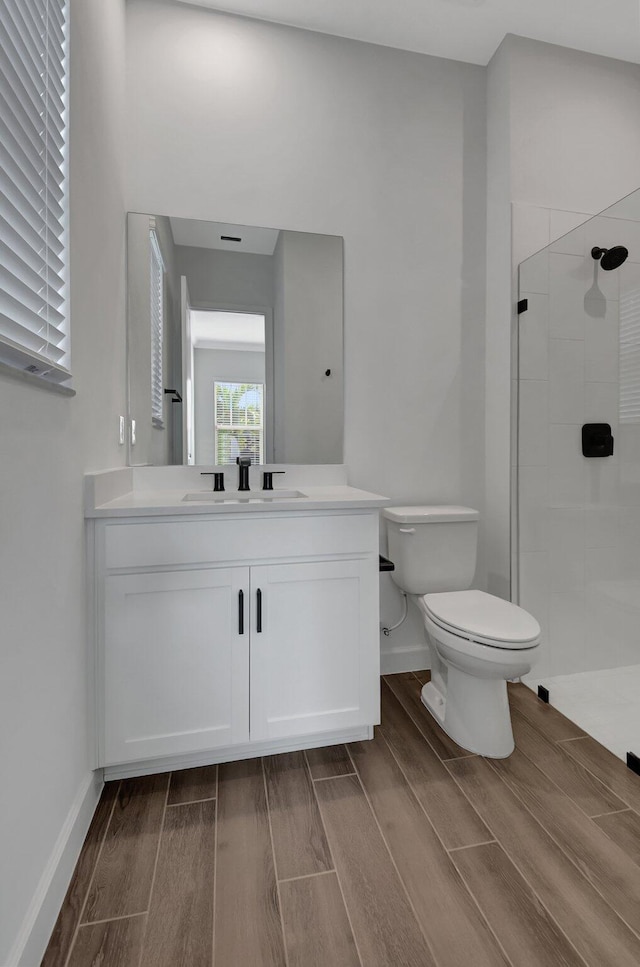 bathroom featuring vanity, toilet, and a tile shower