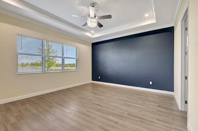 spare room featuring light hardwood / wood-style floors, crown molding, ceiling fan, and a tray ceiling