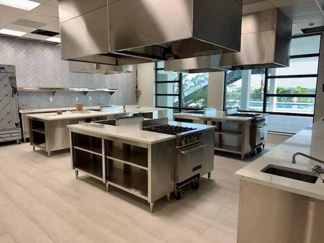 kitchen featuring sink, tasteful backsplash, high end range, island range hood, and a kitchen island