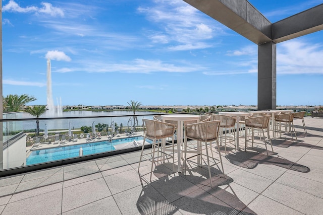 view of patio / terrace featuring a water view, a community pool, and exterior bar