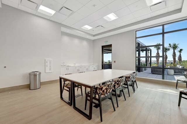 dining room with a drop ceiling, sink, light hardwood / wood-style flooring, and expansive windows