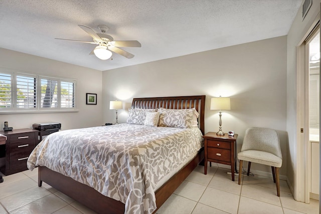 bedroom featuring ceiling fan, light tile patterned floors, and a textured ceiling