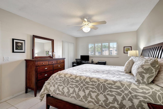 bedroom featuring ceiling fan, light tile patterned floors, and a textured ceiling