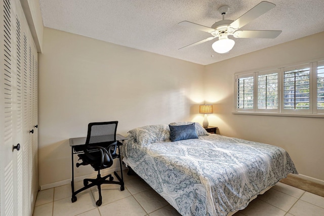 bedroom with a textured ceiling, a closet, tile patterned floors, and ceiling fan