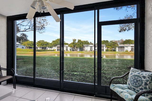 unfurnished sunroom featuring ceiling fan and a water view