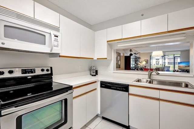 kitchen with white cabinets, light tile patterned floors, sink, and appliances with stainless steel finishes