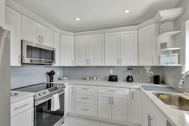 kitchen with open shelves, appliances with stainless steel finishes, white cabinetry, and a sink