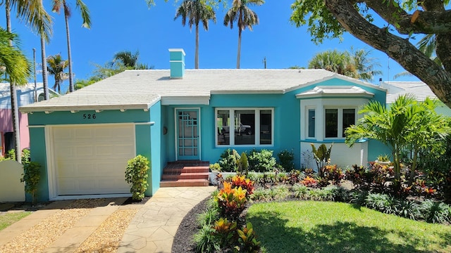 view of front of home featuring an attached garage, a chimney, and stucco siding