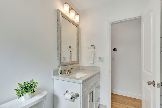 bathroom featuring toilet, vanity, wood finished floors, and baseboards