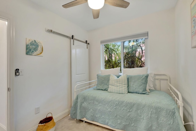 carpeted bedroom with a barn door and ceiling fan