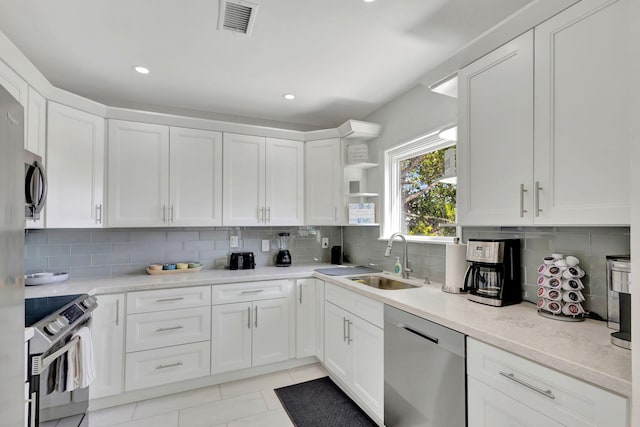 kitchen with backsplash, stainless steel appliances, white cabinetry, and sink