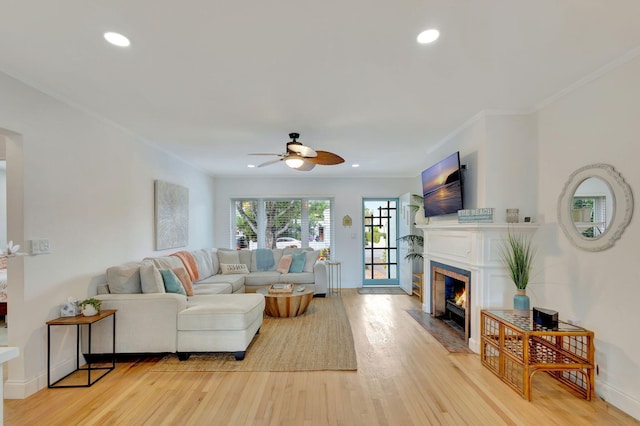 living room with a fireplace with flush hearth, recessed lighting, a ceiling fan, light wood-type flooring, and crown molding